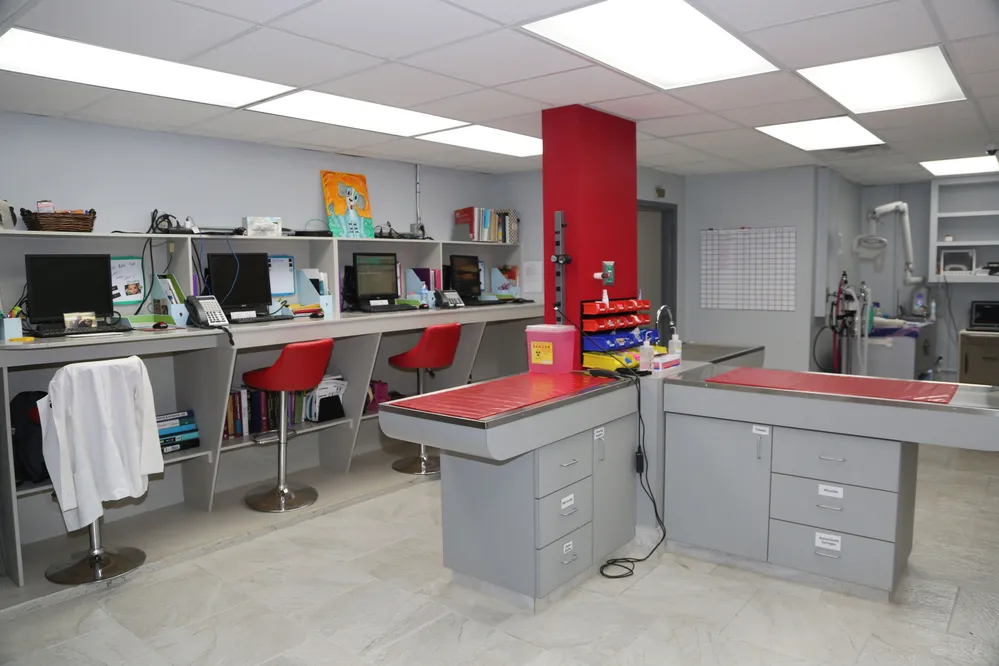 Photo of Animal Care Center of Tupelo Location Back of Office, includes several desks set into the wall with computers and chairs, two exam tables, and various equipment